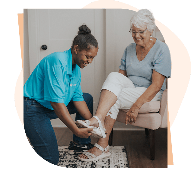 Caregiver assisting senior with putting shoes on