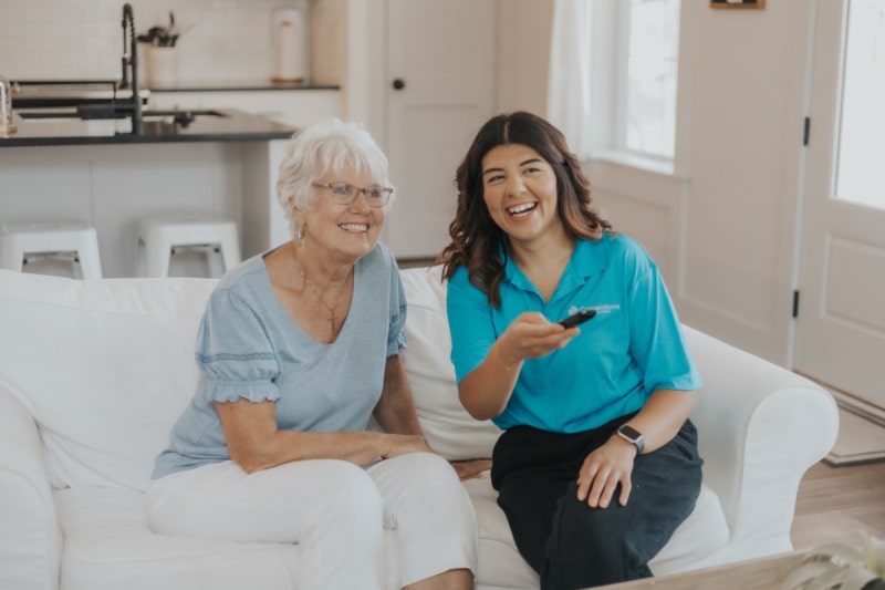 Caregiver and senior watching tv together