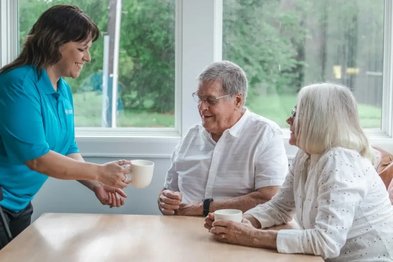 Caregiver handing senior client a cup of coffee